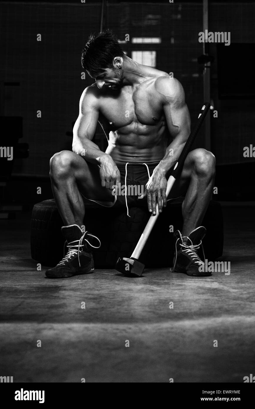 Athletic Man Resting - Entraînement à la salle de sport avec un marteau et le pneu du tracteur Banque D'Images