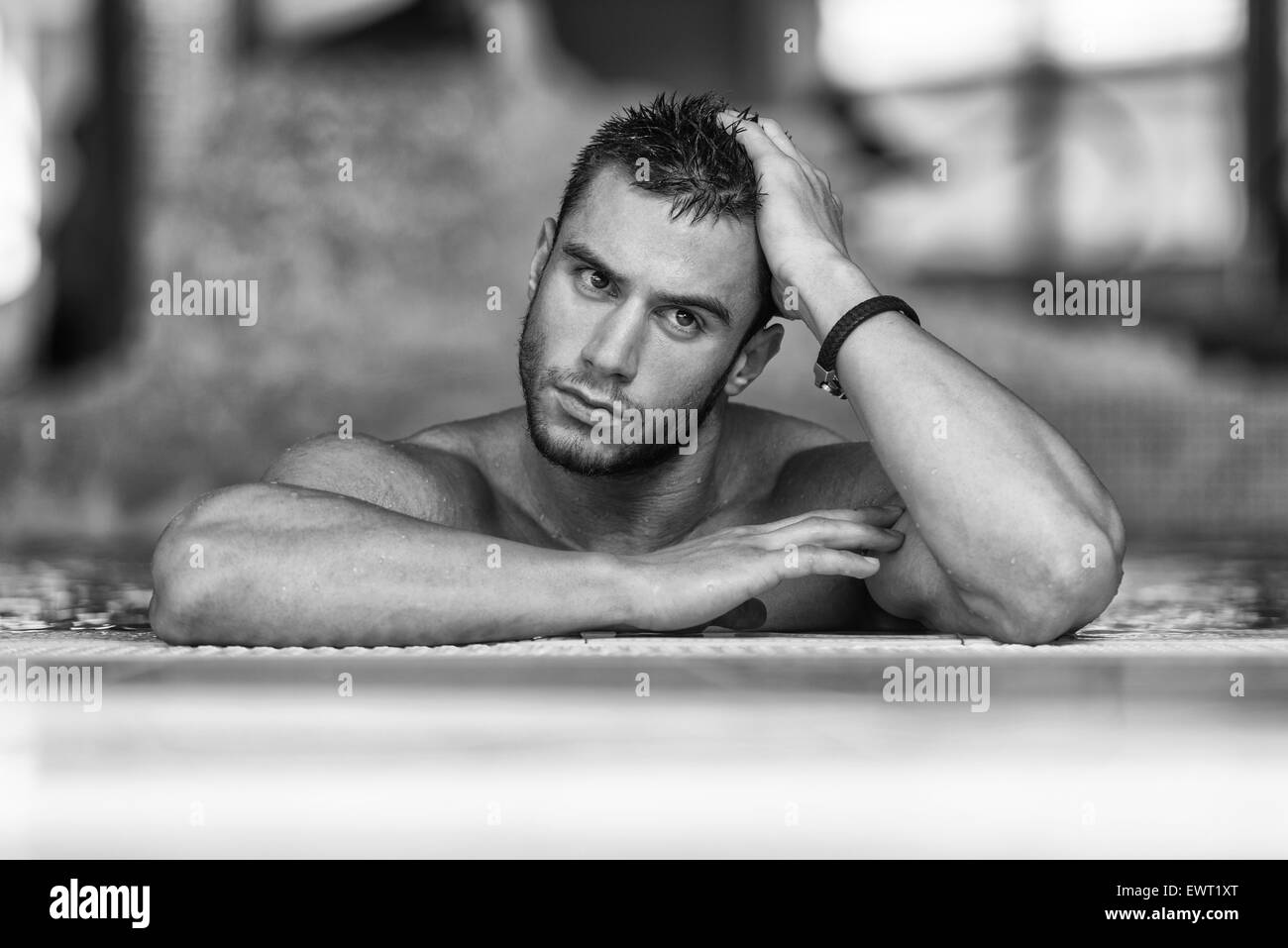 Heureux homme séduisant reposant détendu sur bord de piscine Banque D'Images