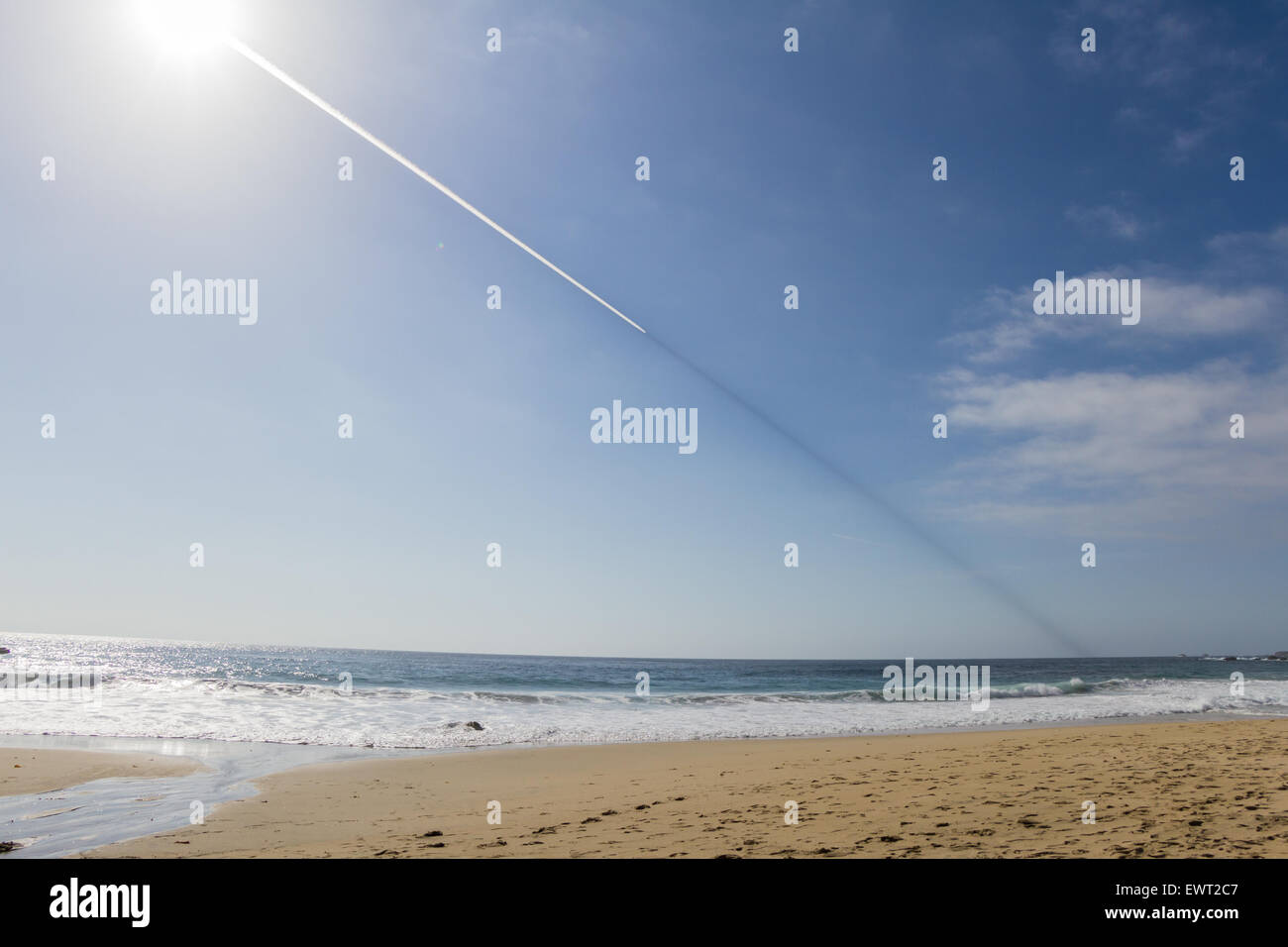 Un sentier étrange dans le ciel au-dessus de la côte de Californie, avec une piste blanche derrière l'avion et une ligne sombre en face, tourné avec un Banque D'Images