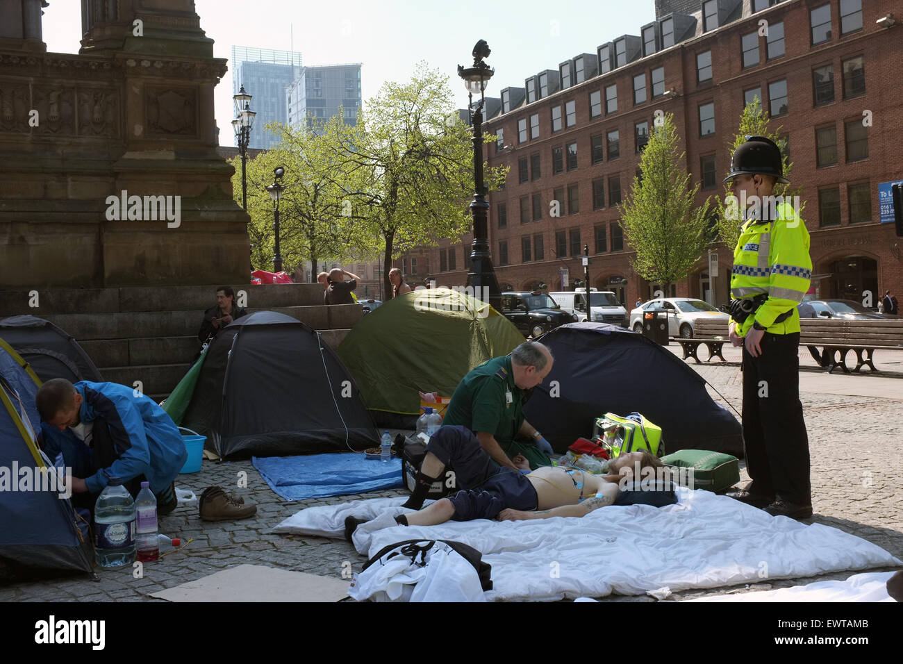 Un paramédic et policier aidant un sans-abri camping protestataires dans Albert Square dans le centre-ville de Manchester England UK Banque D'Images