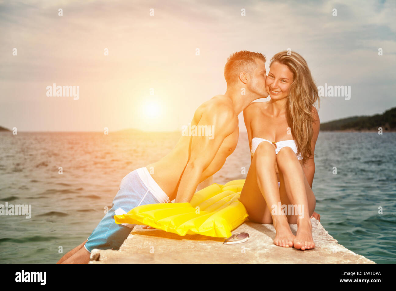 Les jeunes professionnels et couple romantique baiser sur une plage au coucher du soleil Banque D'Images