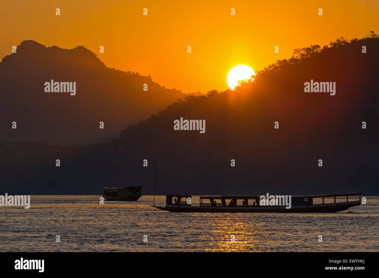 Le coucher du soleil et ferry boats sur le fleuve du Mékong, Luang Prabang, Laos Banque D'Images