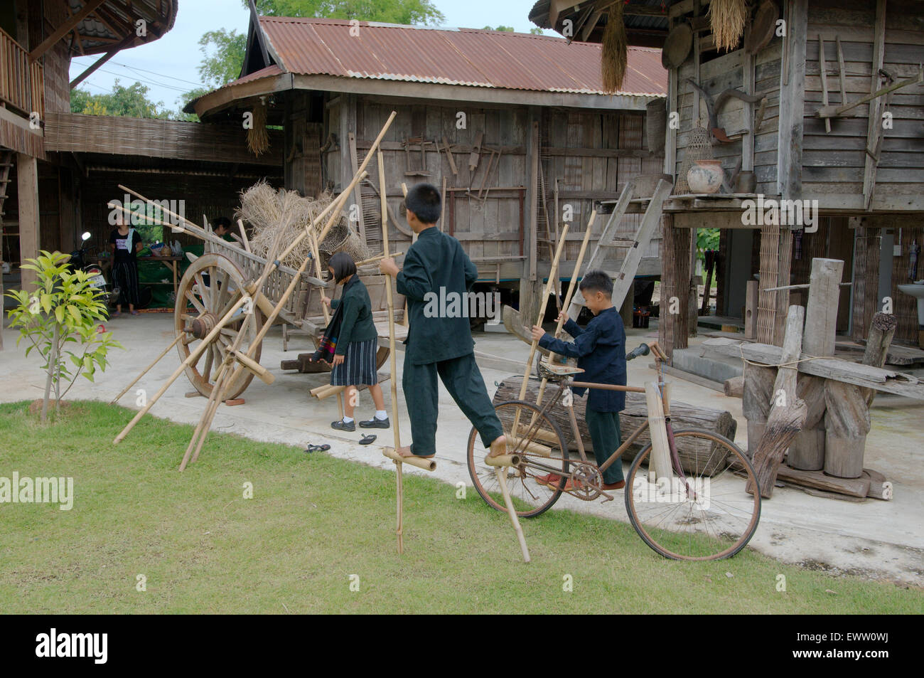 Enfants Tai Dam apprendre à marcher sur des échasses en bambou, province de Loei, Thaïlande Banque D'Images