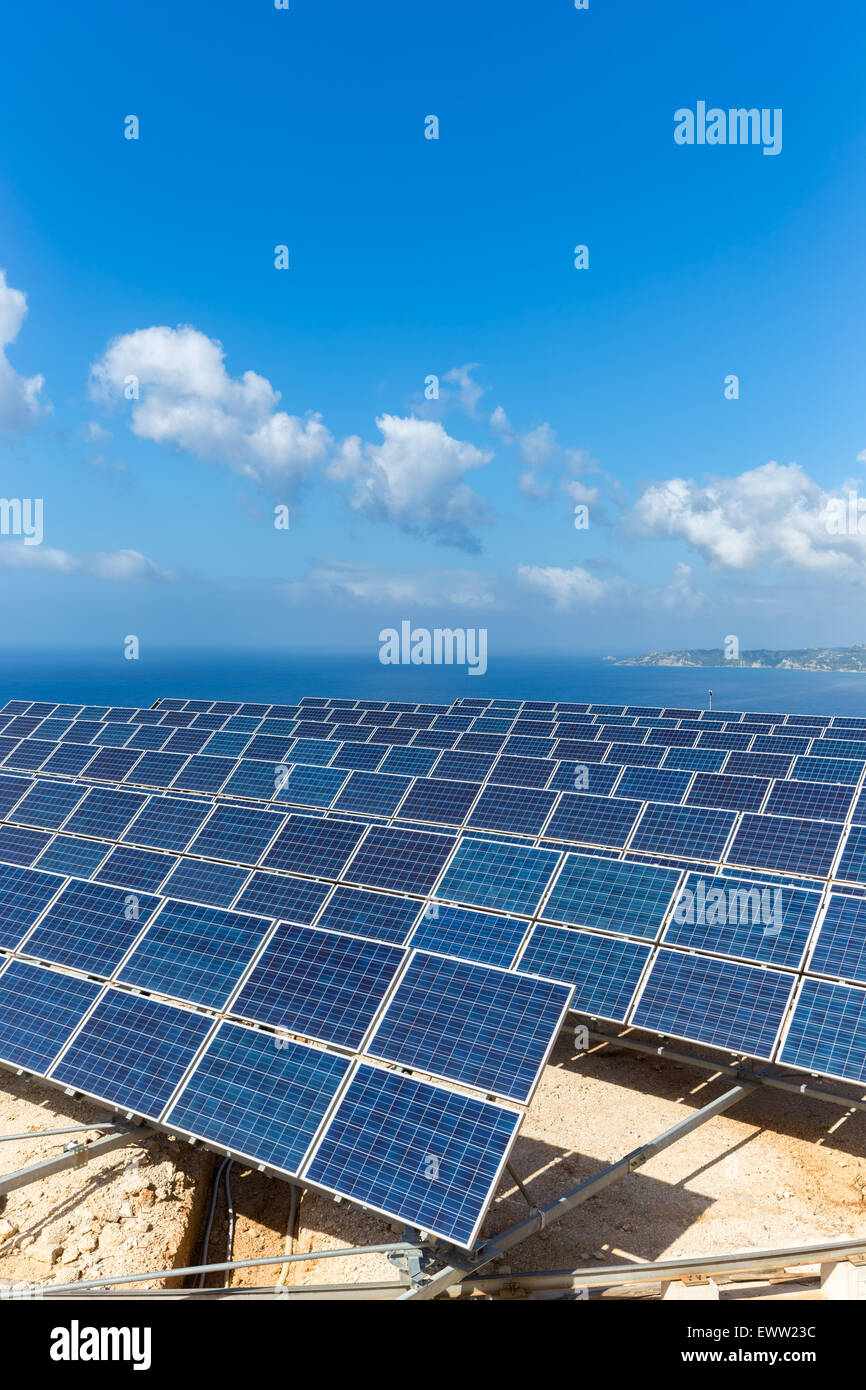 Domaine de nombreux panneaux solaires bleu en rangées près de la mer à l'autre en Grèce avec ciel bleu Banque D'Images