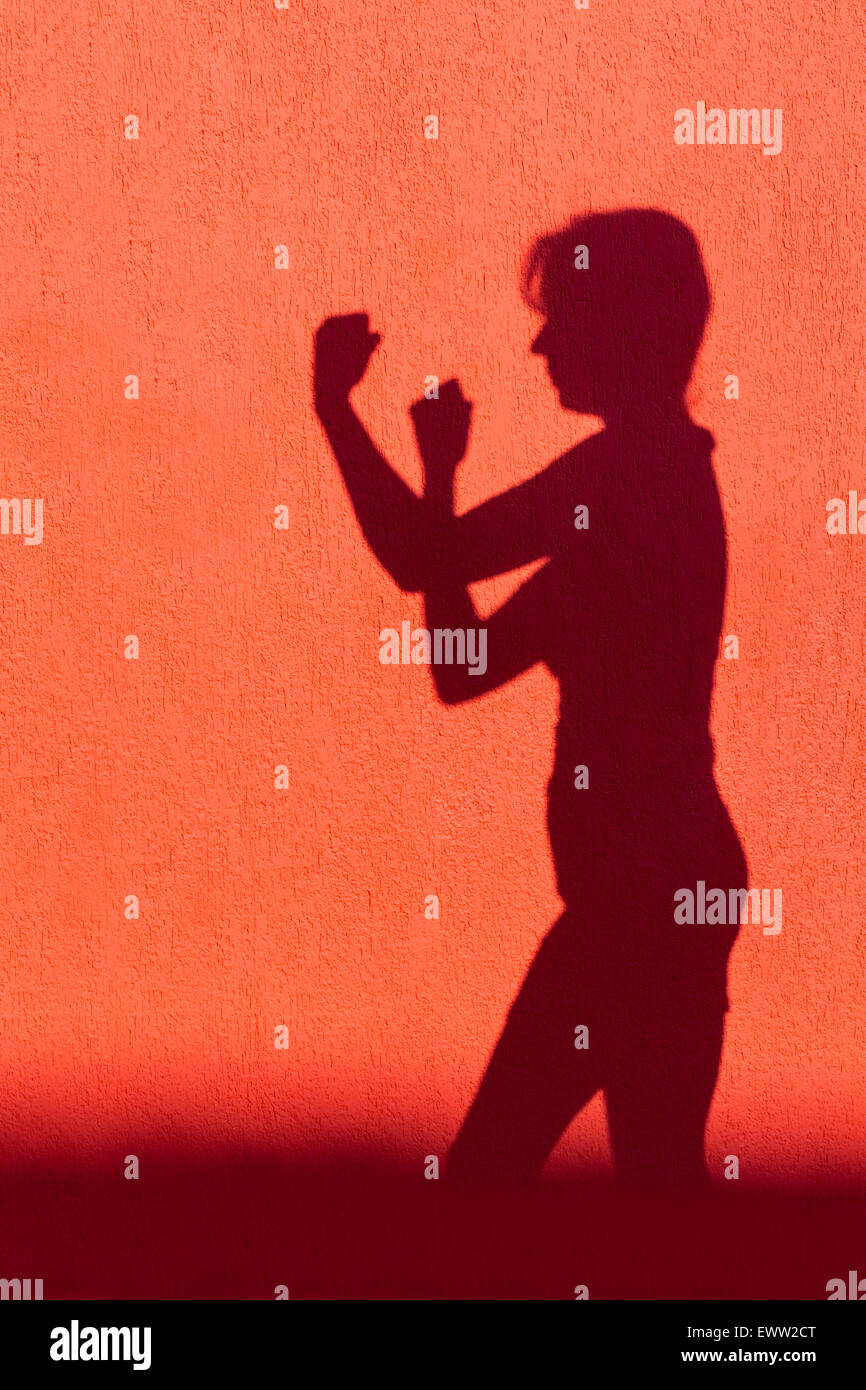 Silhouette de femme adulte montrant les poings sur le mur rouge prêt à combattre Banque D'Images