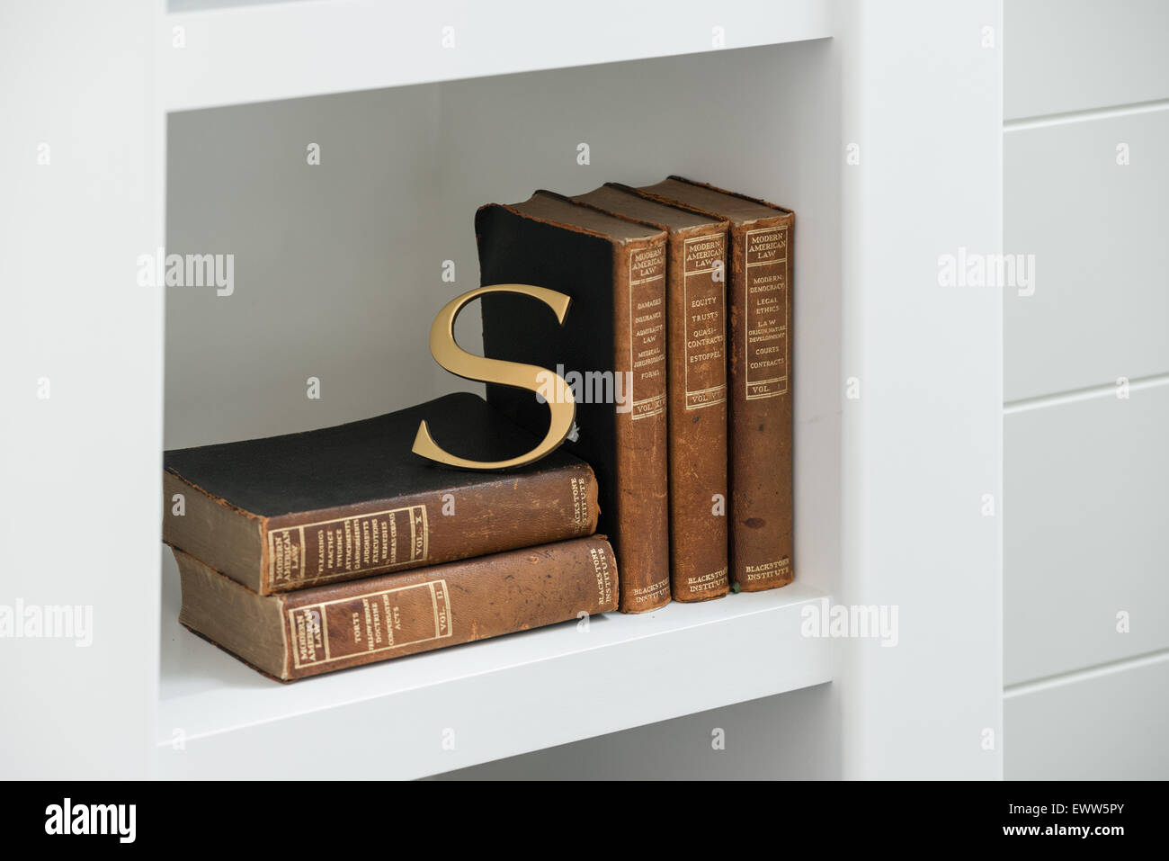 Lettre d'or s'appuyant sur les livres de droit antique à l'intérieur d'étagères modernes Banque D'Images