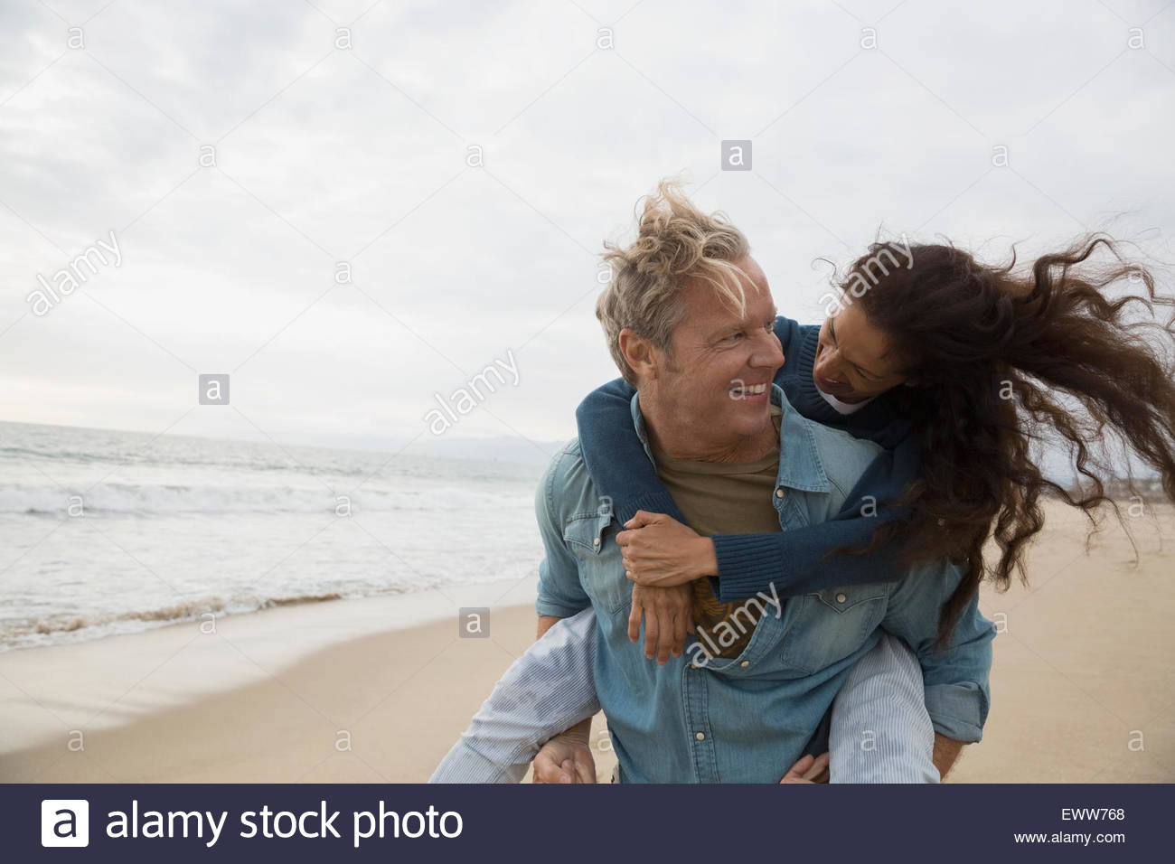 Playful couple piggybacking on beach Banque D'Images