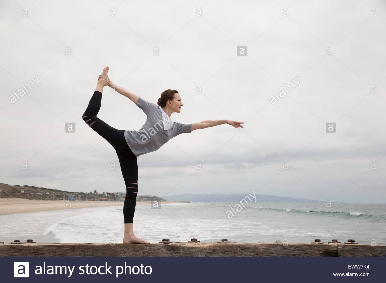 Woman doing yoga posture du danseur king on beach Banque D'Images