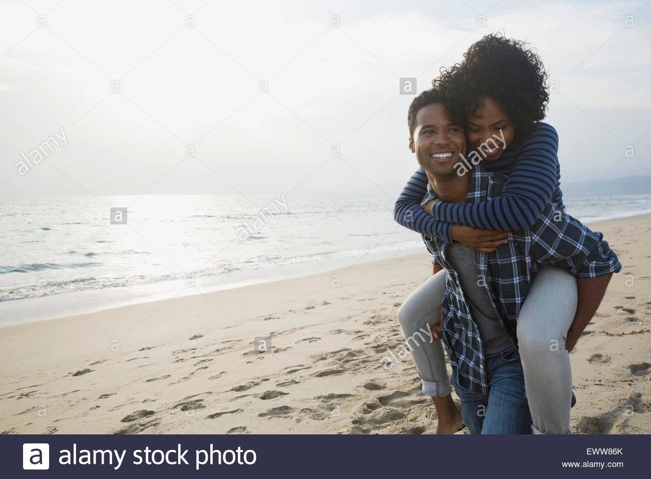 Couple piggybacking on sunny beach Banque D'Images