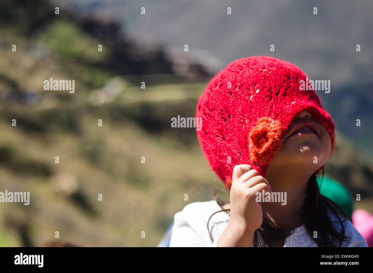 Jeune fille au Pérou couvrant son visage avec une red hat. A lieu à Pisac, une ruine archéologique. Banque D'Images