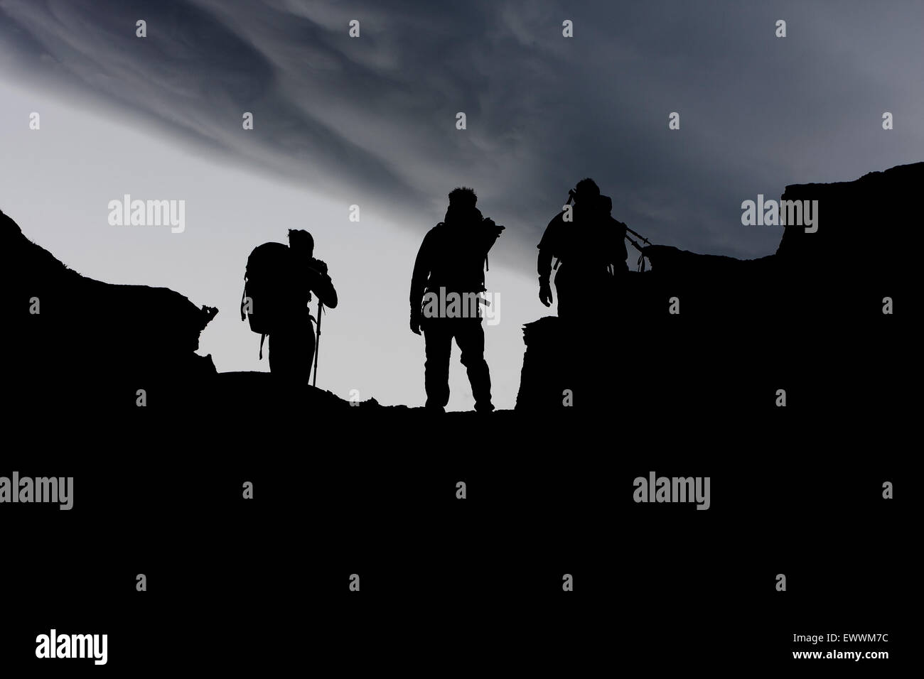 Silhouette de personnes randonnées en montagne, défini dans un ciel dramatique Banque D'Images