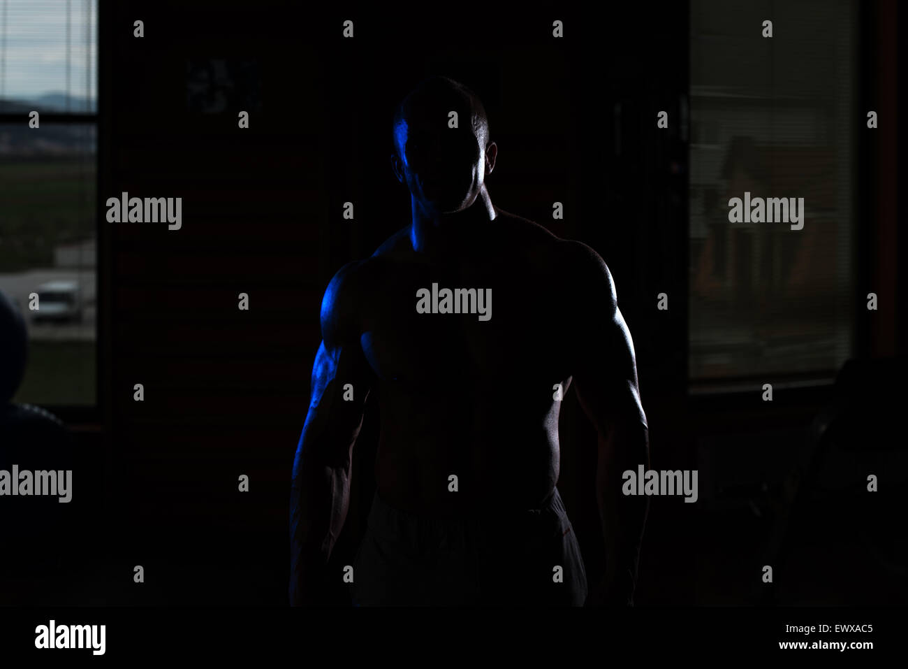 Jeune homme musclé siluet Flexing Muscles Banque D'Images