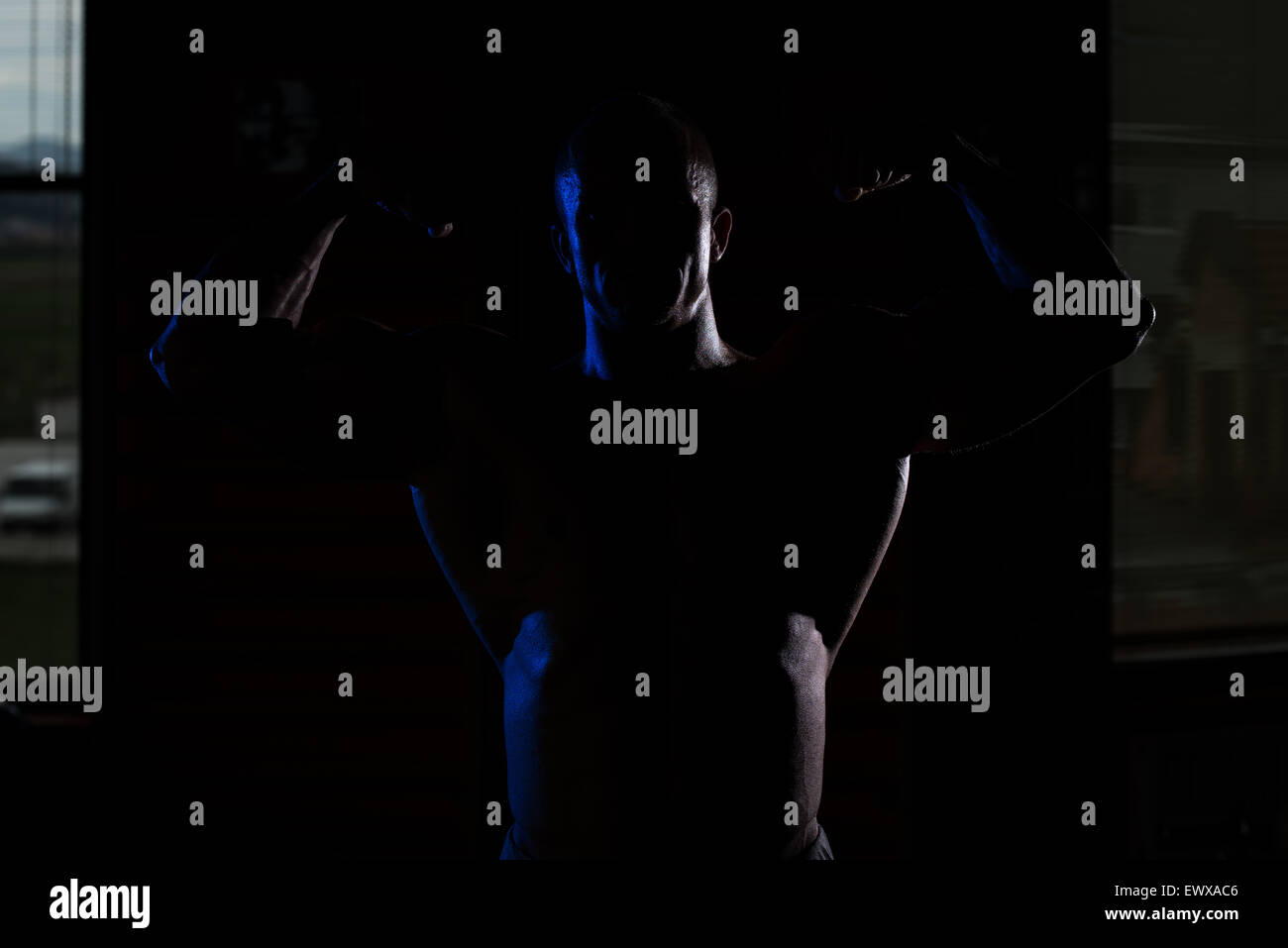 Jeune homme musclé siluet Flexing Muscles Banque D'Images