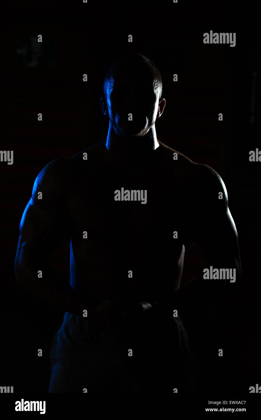 Jeune homme musclé siluet Flexing Muscles Banque D'Images