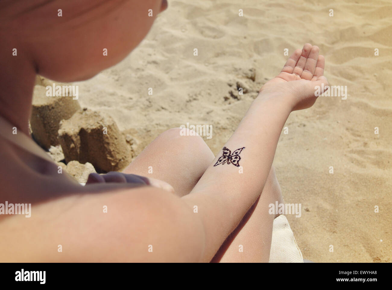 Fille sur la plage avec un papillon temporaire tatouage sur son bras Banque D'Images