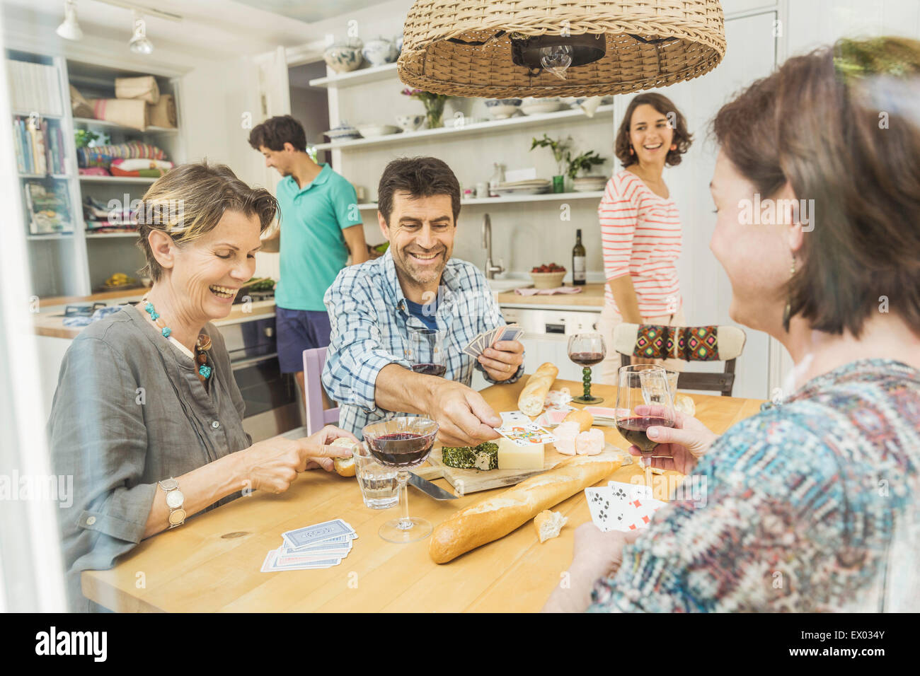 Cinq amis adultes jouent aux cartes à une table à manger Banque D'Images