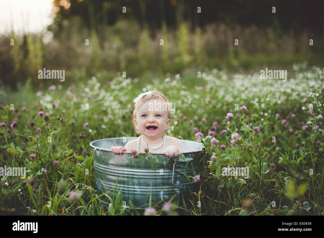 Baby Girl baignant dans un bain d'étain dans une prairie de fleurs sauvages Banque D'Images