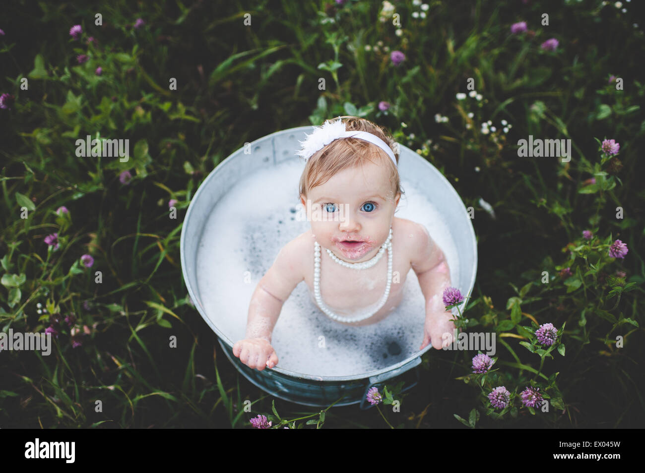 Vue de dessus de petite fille baignant dans un bain d'étain dans une prairie de fleurs sauvages Banque D'Images