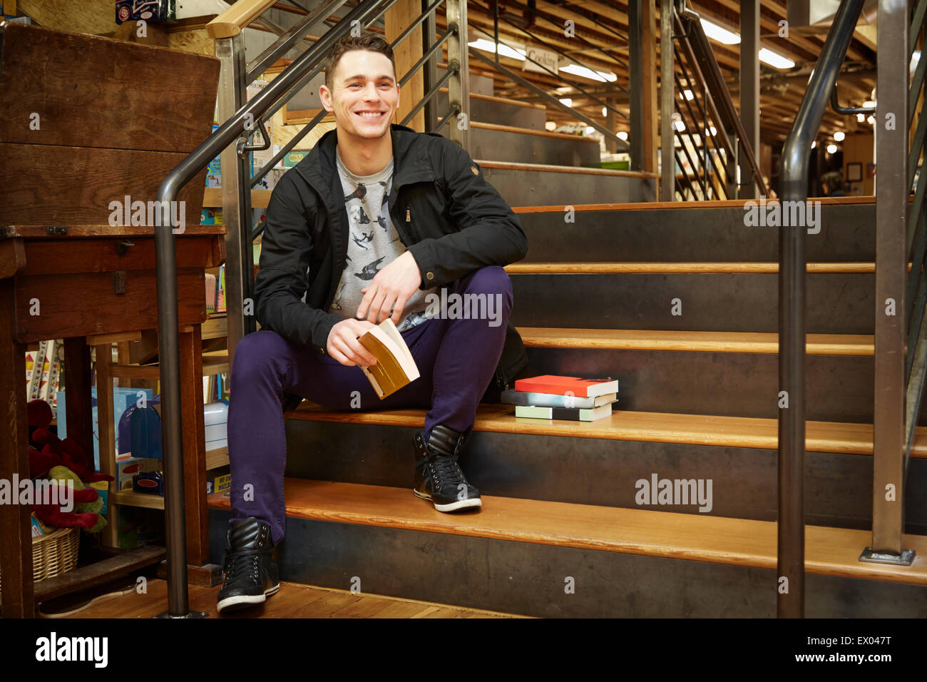 Portrait de jeune homme assis sur l'escalier book store Banque D'Images
