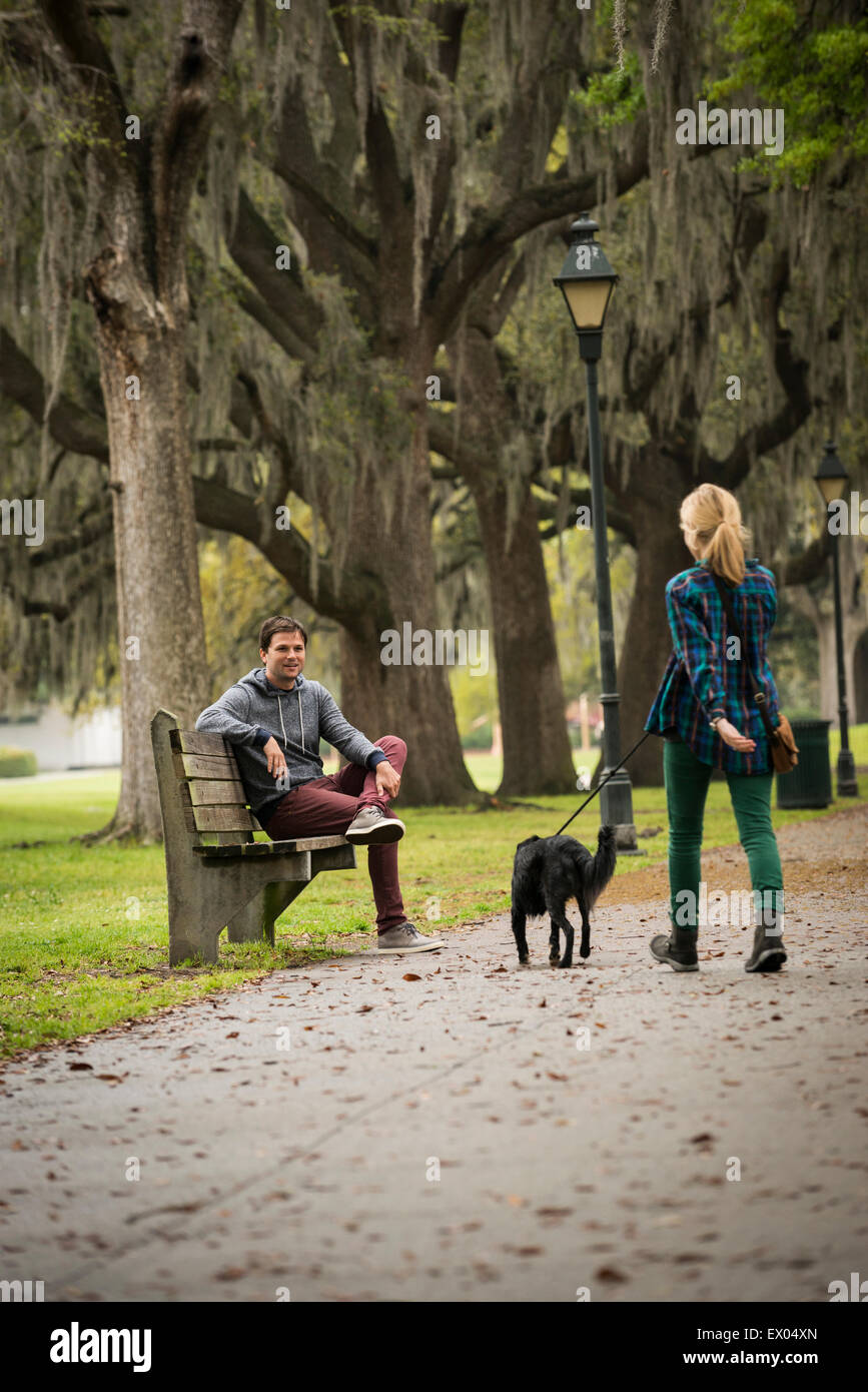 Man on park bench, woman walking dog, Savannah, Georgia, USA Banque D'Images