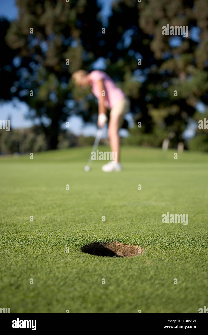 Jeune femme jouant au golf, focus on foreground Banque D'Images