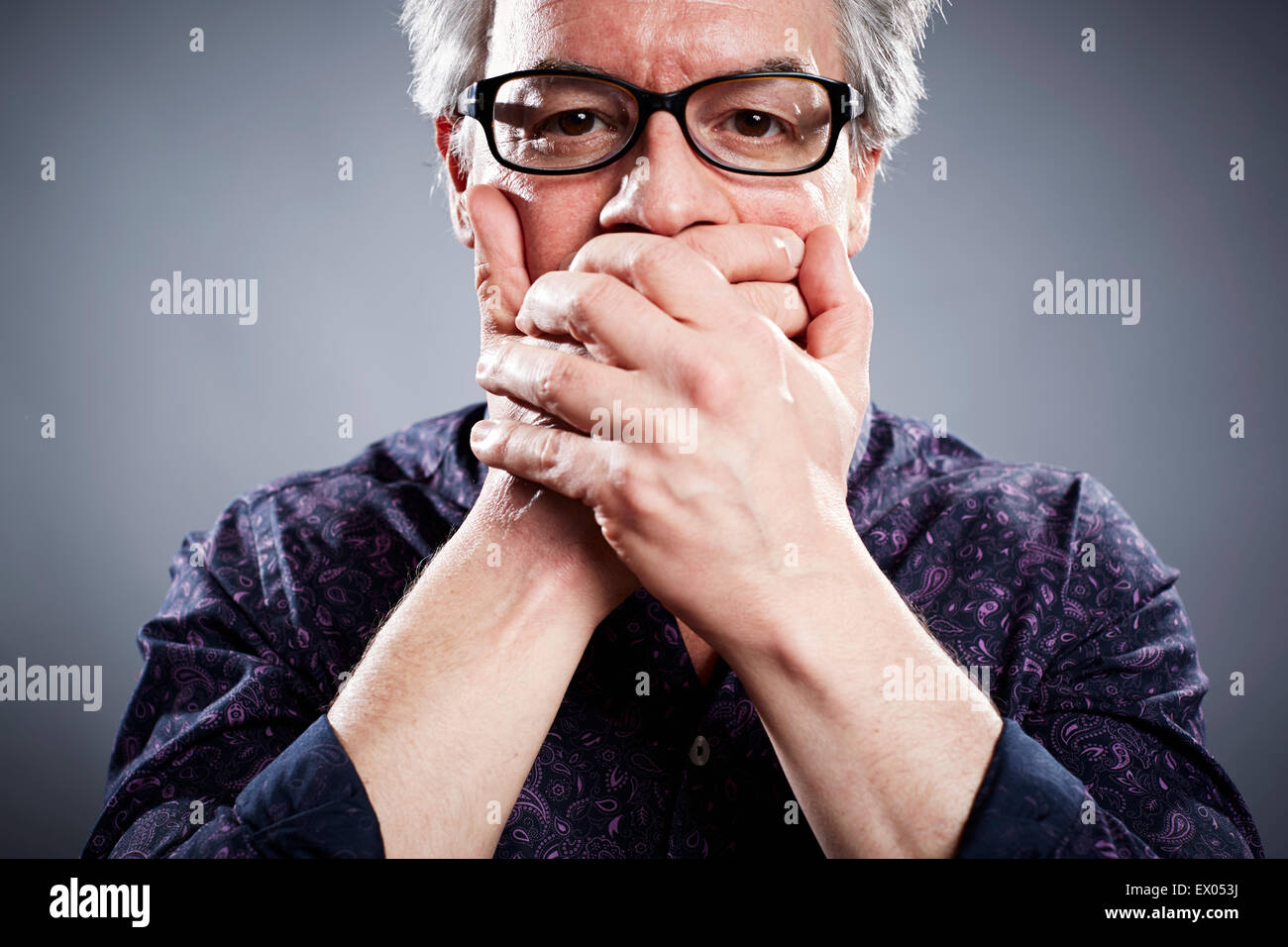 Studio portrait of businessman with hands couvrant la bouche Banque D'Images