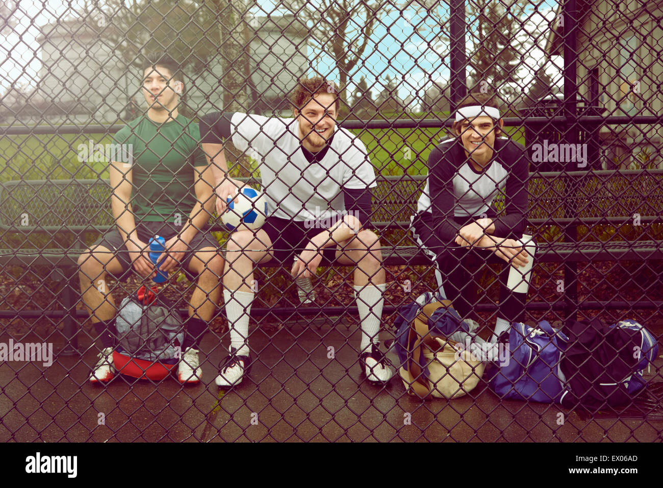 Portrait de trois joueurs de football masculin assis derrière un grillage de sécurité Banque D'Images