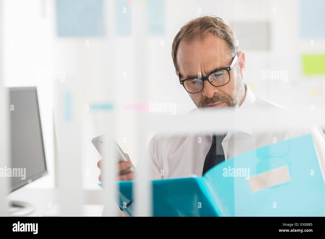 Businessman reading paperwork et using smartphone Banque D'Images