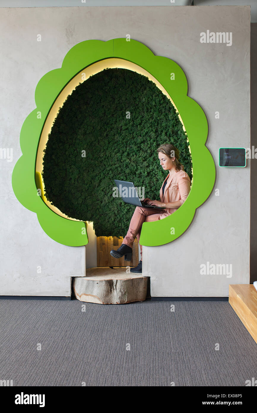 Designer working on laptop in office space en forme d'arbre Banque D'Images