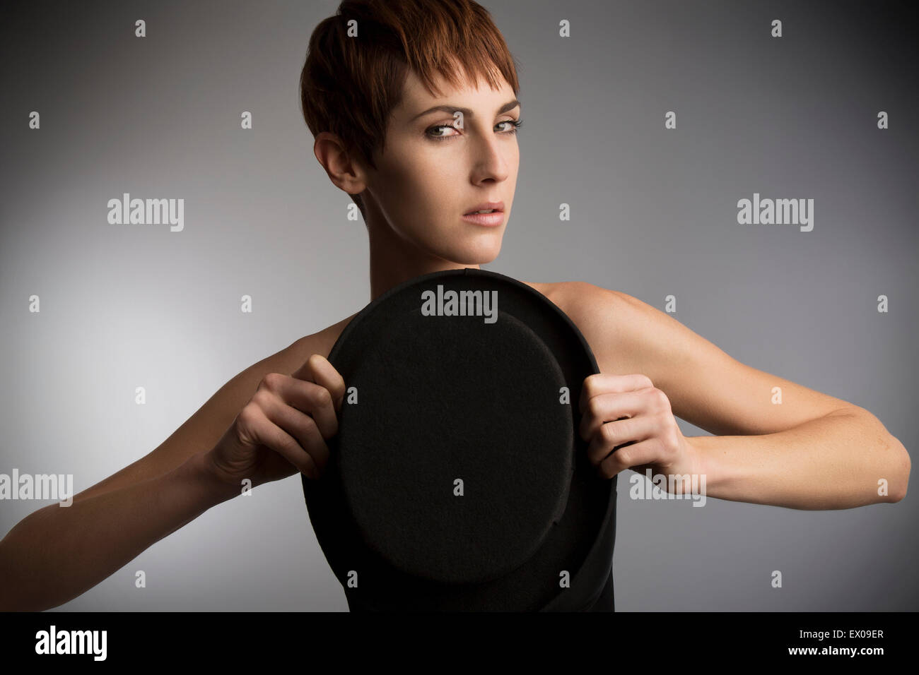 Studio portrait of woman holding top hat en face de la poitrine Banque D'Images