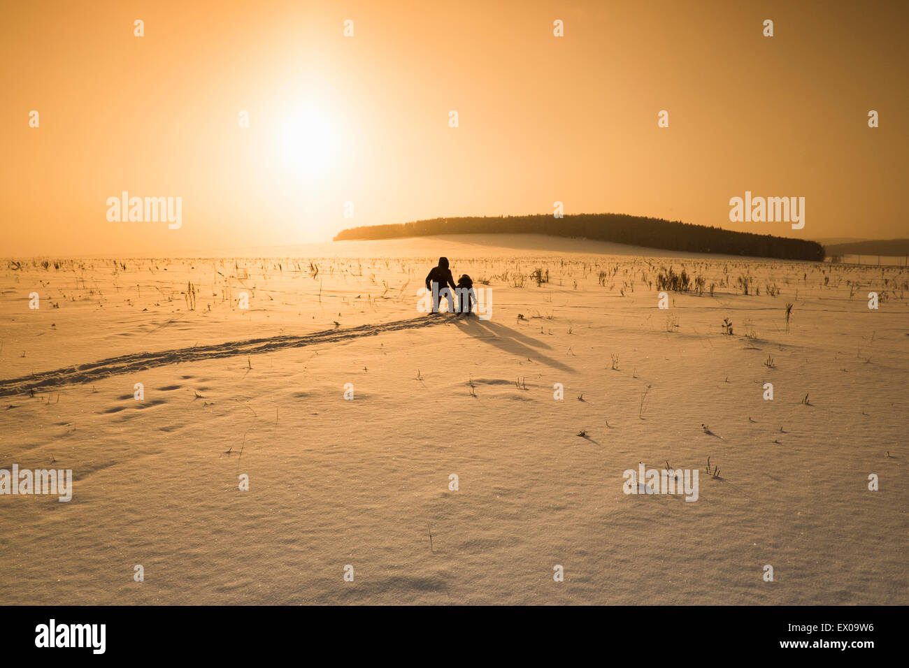 Silhouette d'homme et fils de marcher dans la neige couverts au coucher du soleil, Sarsy village, oblast de Sverdlovsk, en Russie Banque D'Images