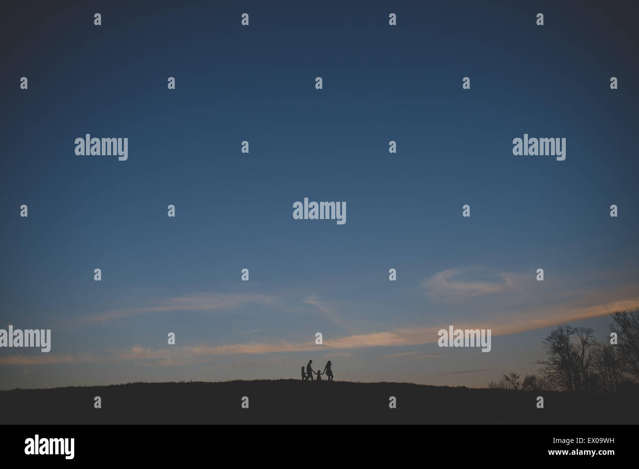 La silhouette vue des parents avec son fils et sa fille se promener sur la colline au crépuscule Banque D'Images