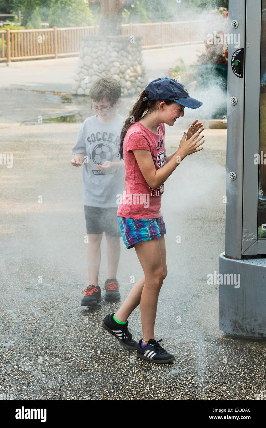 Les enfants se rafraîchir avec l'aide d'une brume rafraîchissante à la machine d'un parc. Banque D'Images