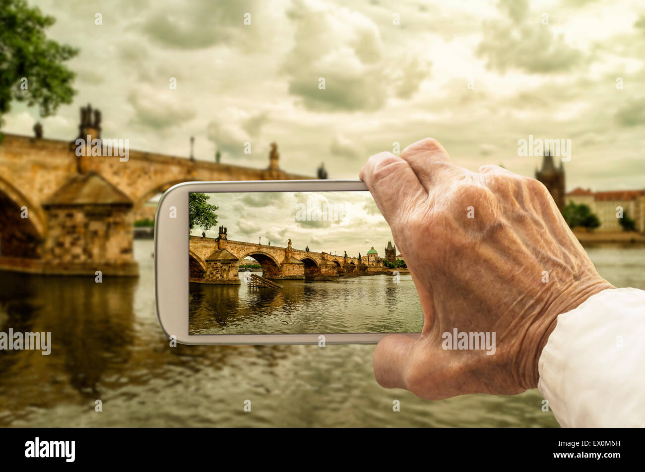 La vieille prend une photo du pont Charles à Prague, République tchèque, le téléphone intelligent. Focus sélectif. Banque D'Images