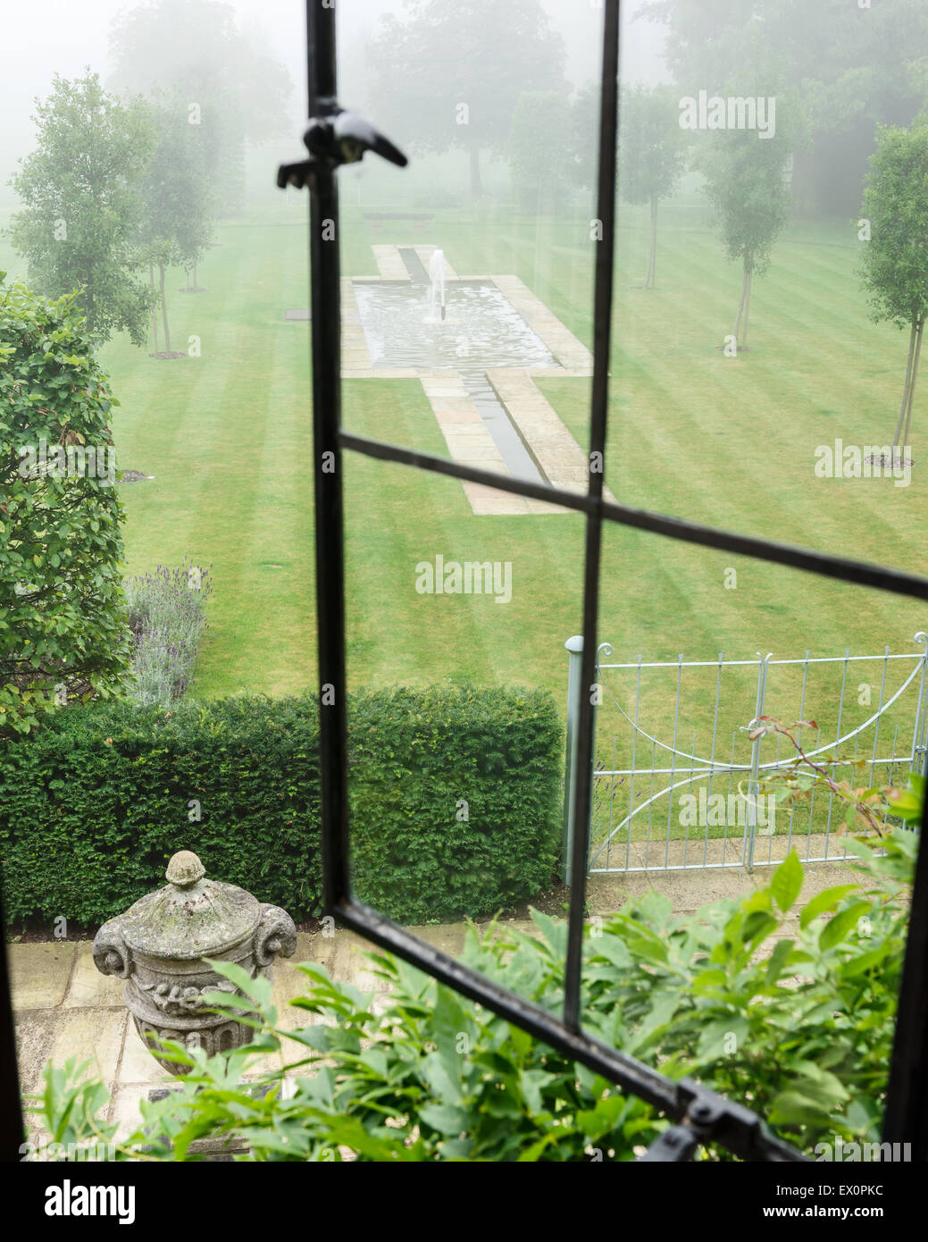 Vue à travers la fenêtre ouverte sur la pelouse avec étang en forme de croix et de la fontaine Banque D'Images