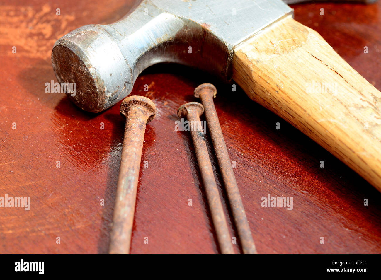 Trois vieux clous et un marteau sur le dessus d'un atelier en bois tableau Banque D'Images