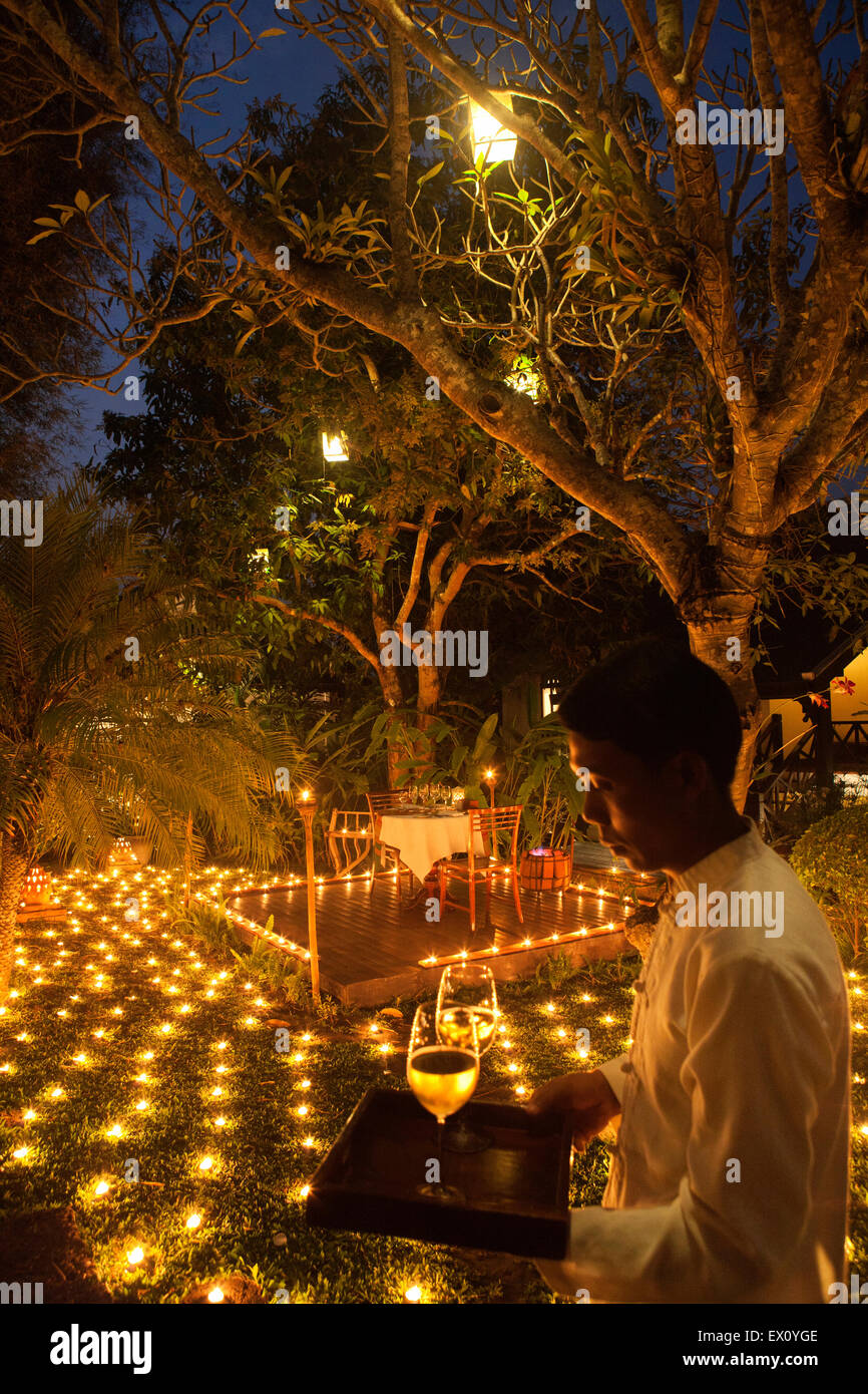 Un dîner aux chandelles spécial 500 avec serveur au crépuscule. La Residence Phou Vao. Luang Prabang, Laos. Banque D'Images