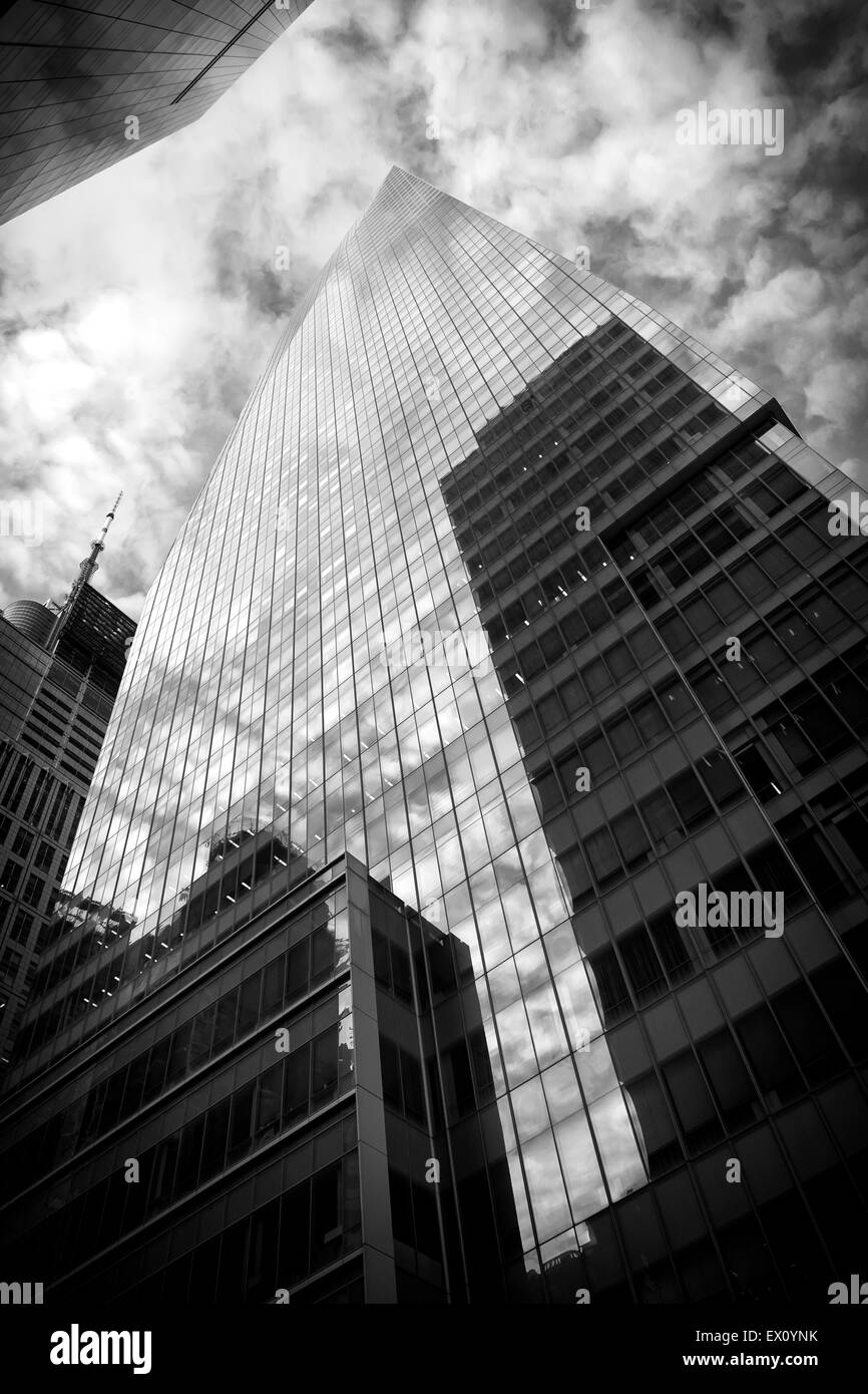 Façade miroir gratte-ciel de New York contre un ciel nuageux en noir et blanc Banque D'Images