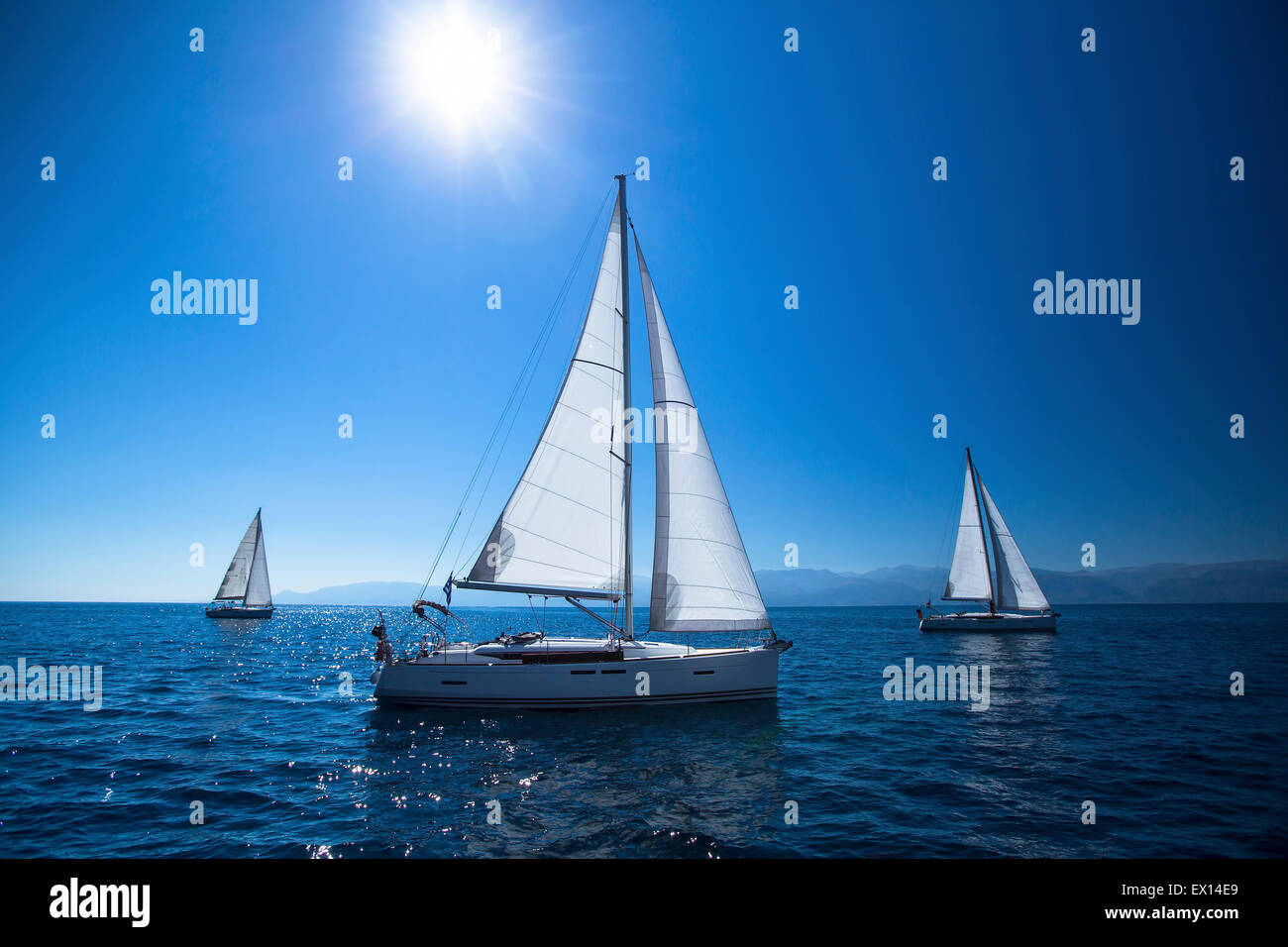 Bateau à voile yachts avec voiles blanches dans la mer ouverte. Midi, le ciel bleu et le soleil au zénith. Banque D'Images