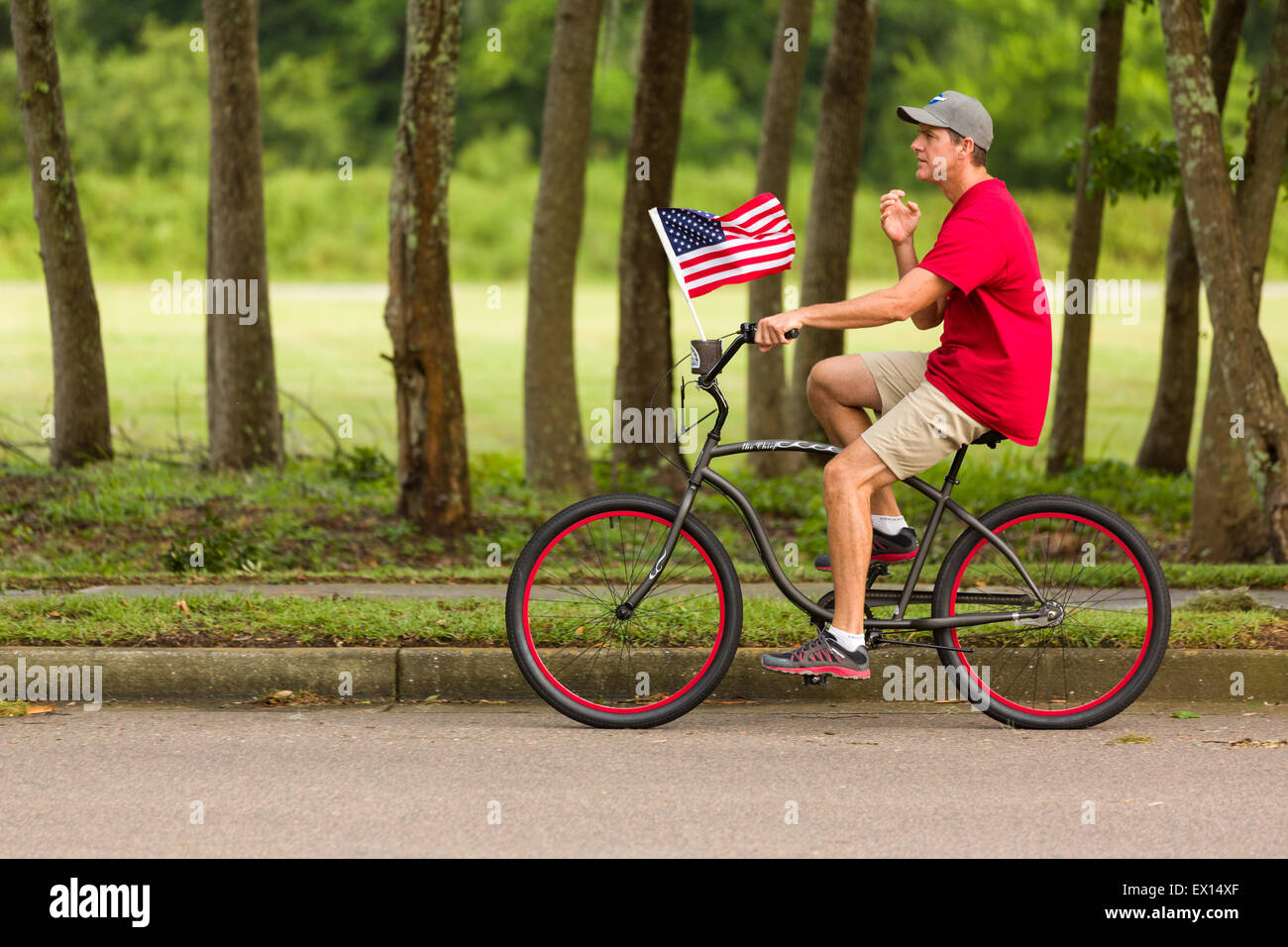 Un cycliste rides passé avec le drapeau américain au cours de l'île de Daniel ndependence Day Parade le 3 juillet 2015 à Charleston, Caroline du Sud. Banque D'Images