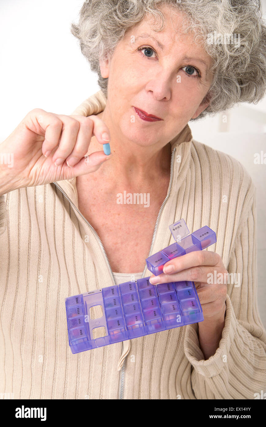 Parution du modèle. Senior woman holding a comprimé et d'un comprimé contenant. Banque D'Images