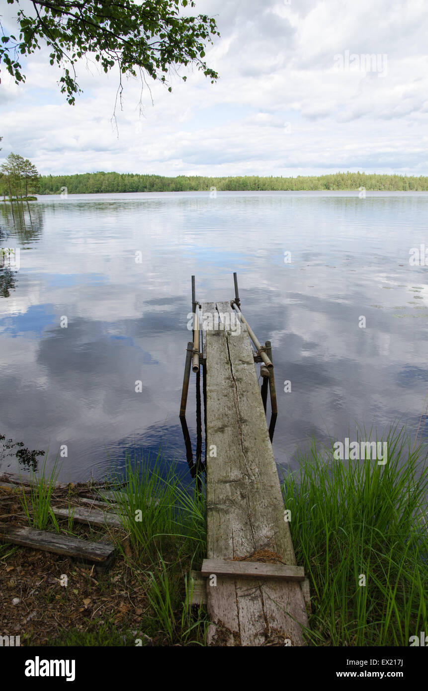 Old weathered jetée en bois dans un lac calme avec des réflexions en Suède Banque D'Images