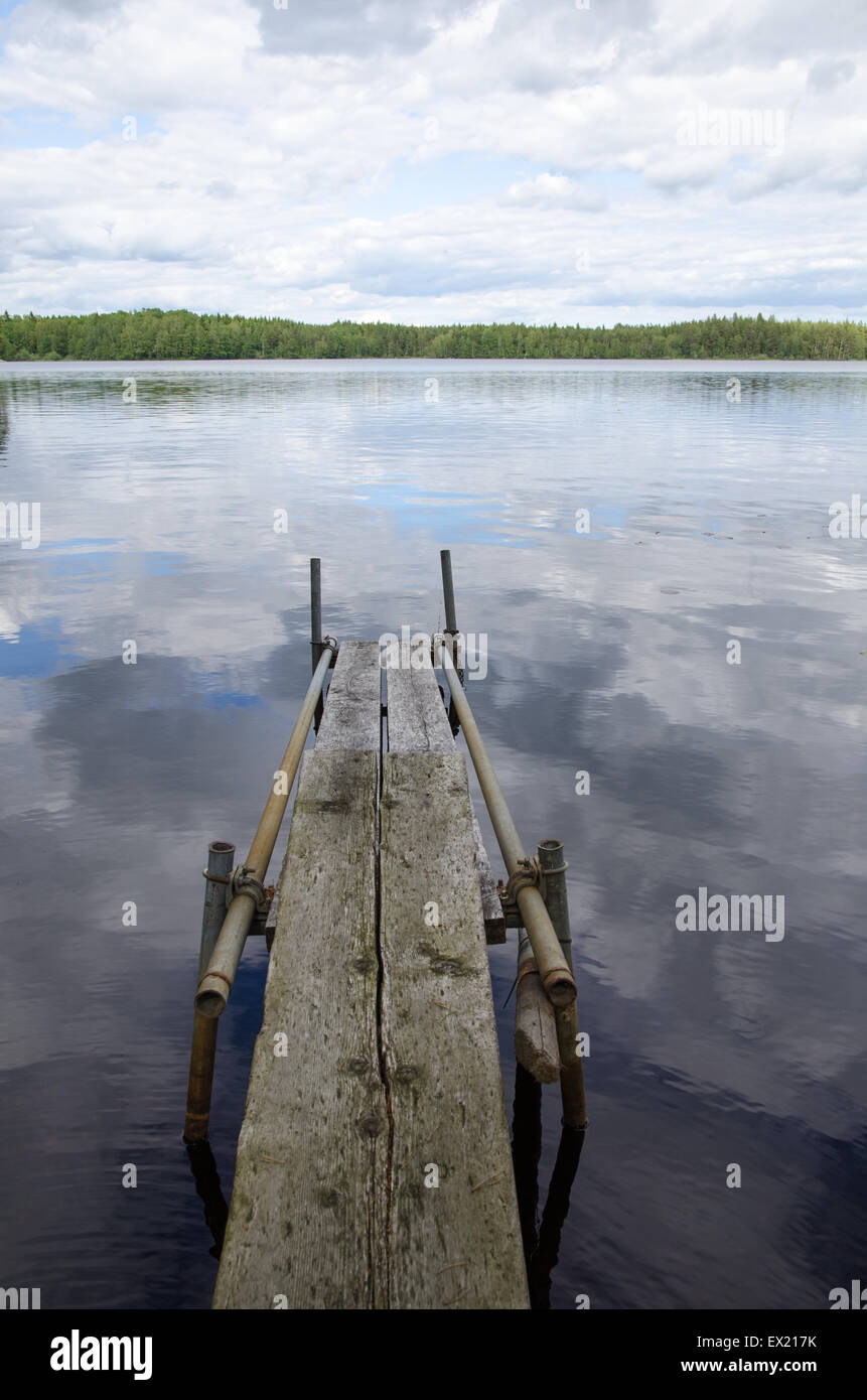 Old weathered wooden pier dans un lac calme avec des réflexions en Suède Banque D'Images