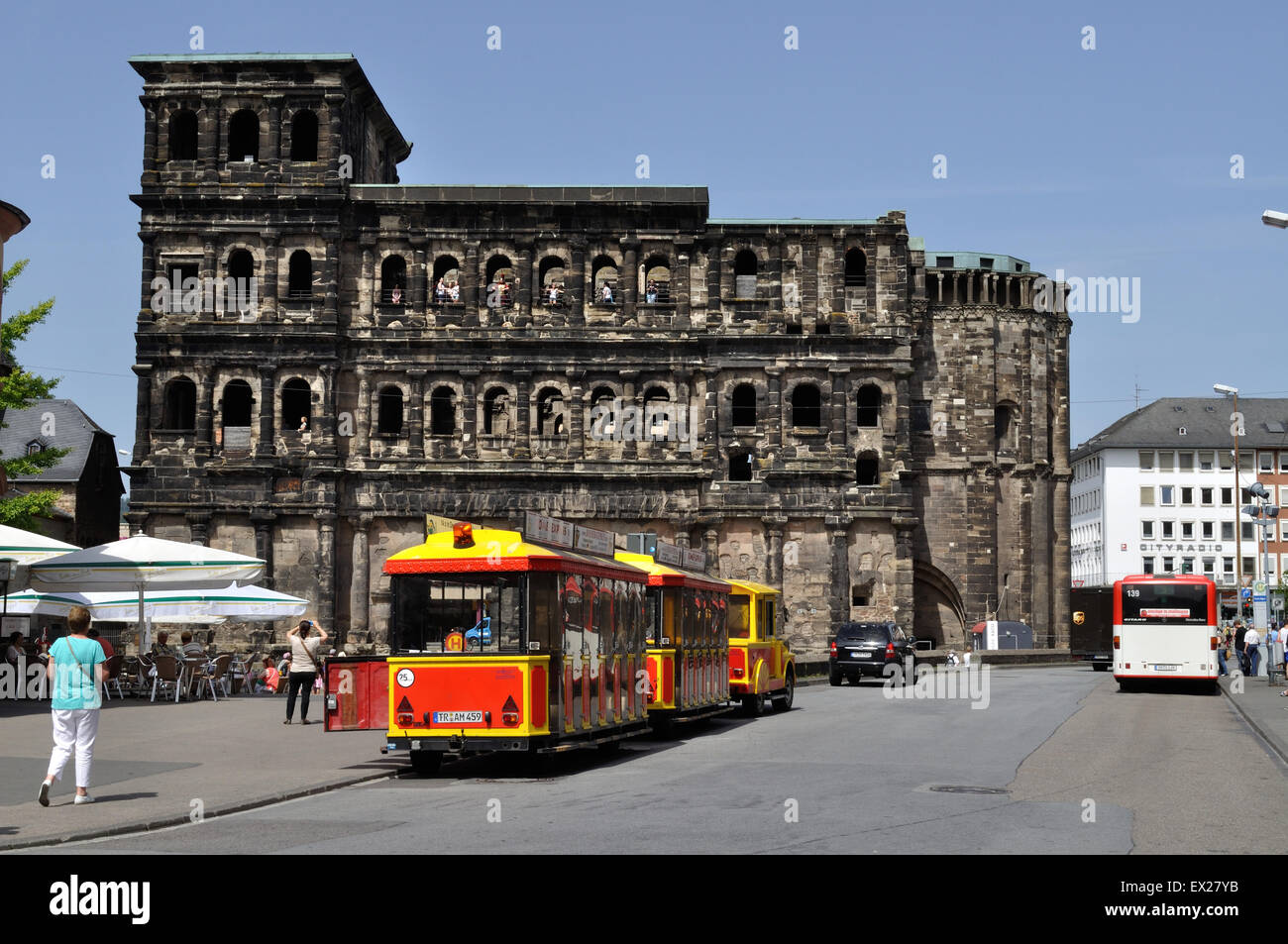 Un petit train touristique attend que coutume à la Porta Nigra, une ancienne porte romaine de Trèves en Allemagne. Banque D'Images