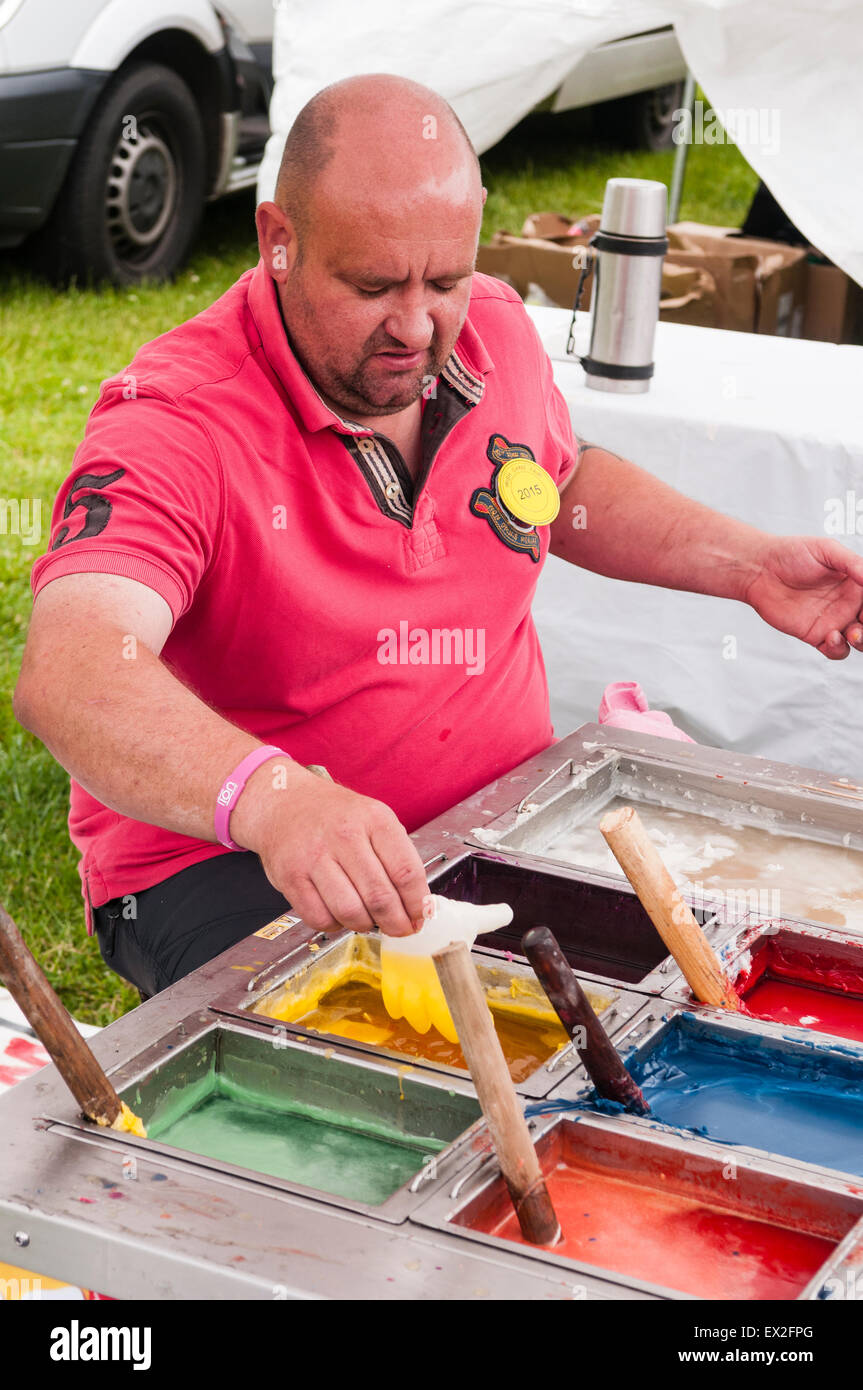 Un homme fait "mains" à l'aide de cire cires multicolores dans un marché Banque D'Images
