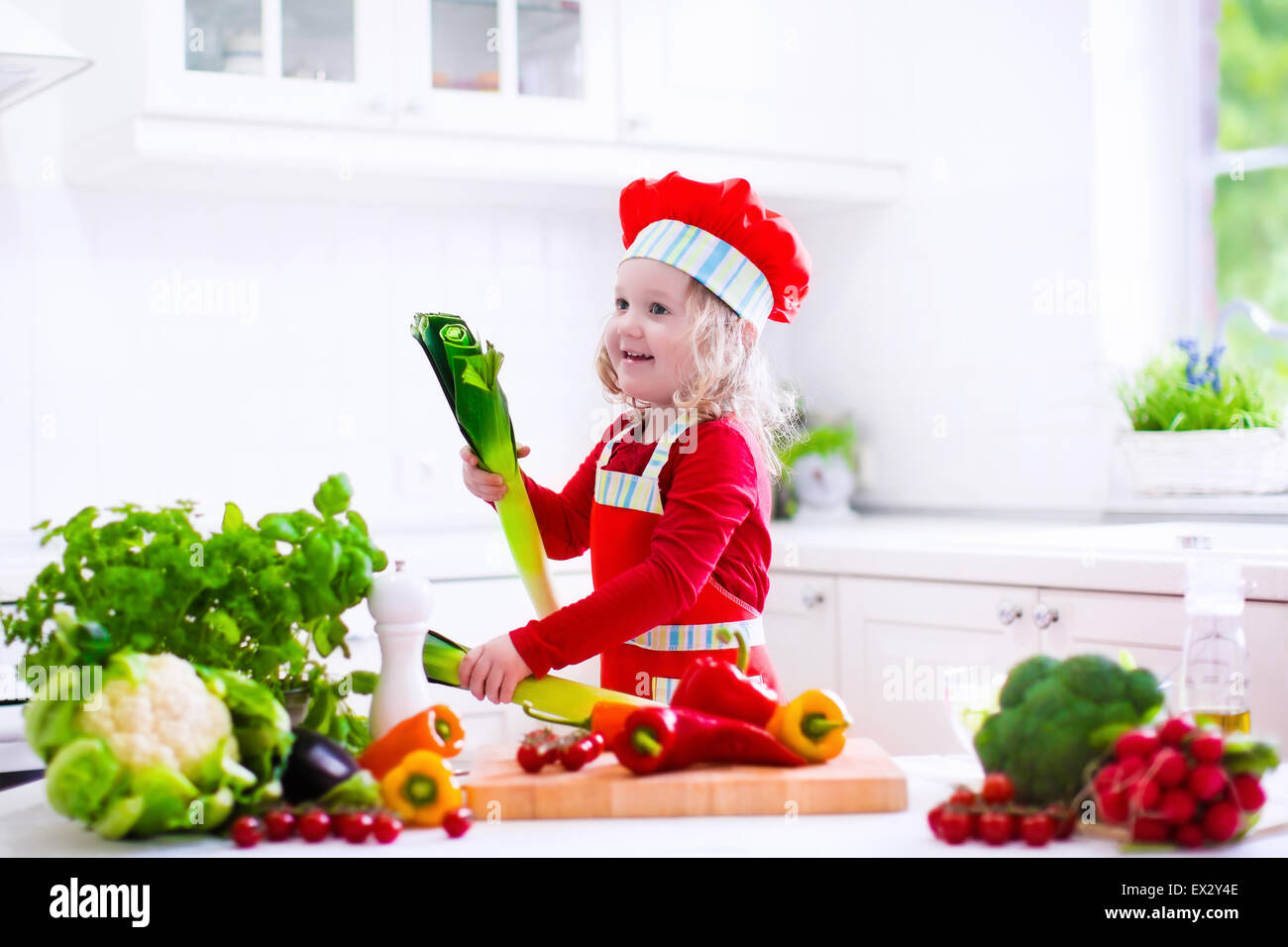 Enfants dans la cuisine une salade de légumes frais dans la cuisine blanche. Faire cuire les légumes pour les enfants déjeuner végétarien. Banque D'Images
