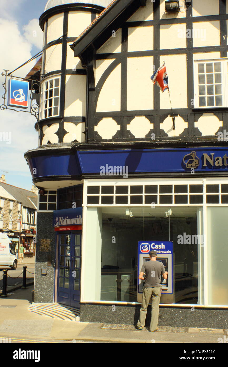 Un homme utilise un distributeur ATM machine à une succursale de la Banque nationale dans le Derbyshire, Angleterre, Royaume-Uni Banque D'Images