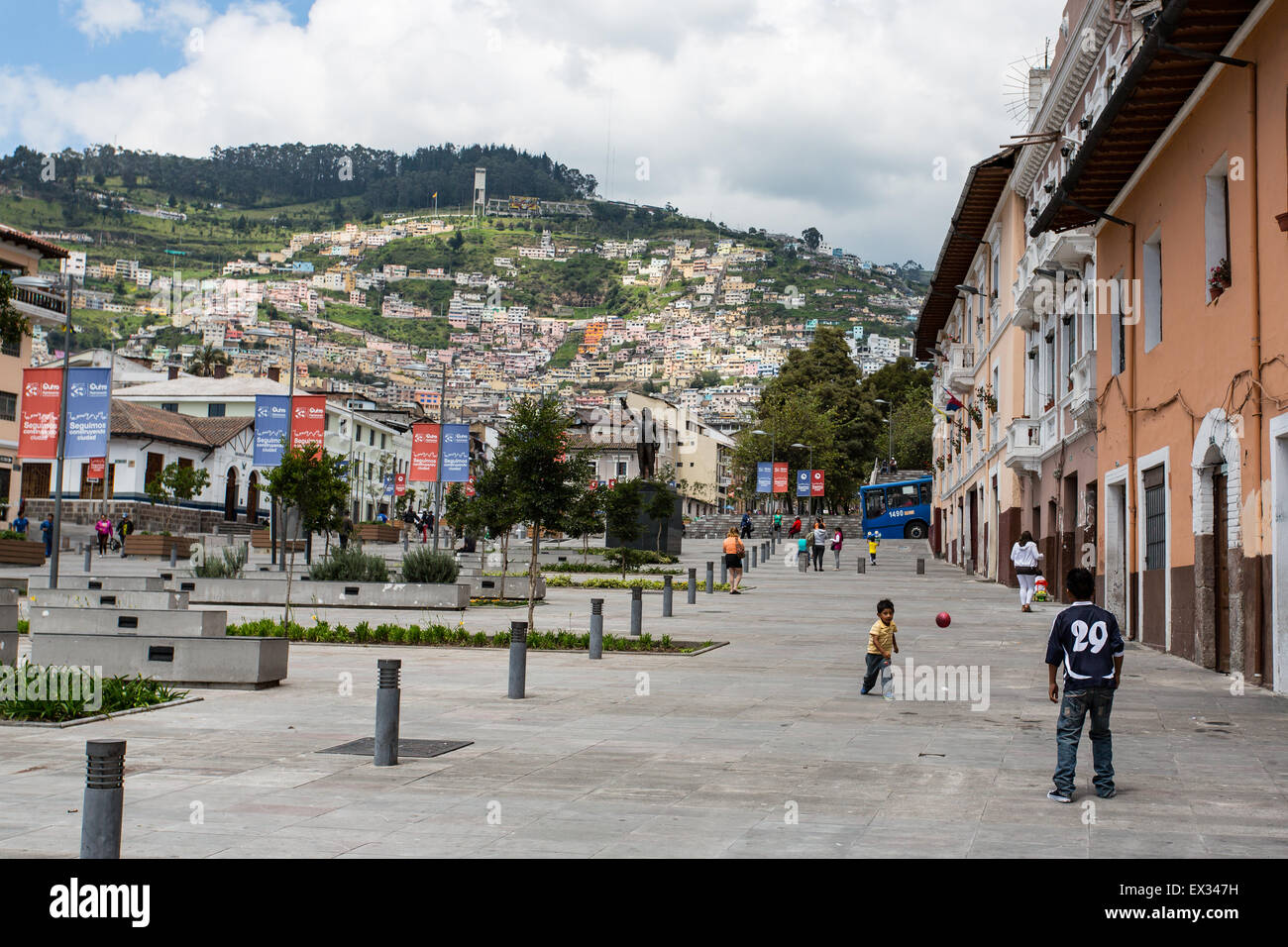 Deux jeunes garçons jouent avec une balle dans les rues de Quito, Équateur, avec des montagnes au loin. Banque D'Images