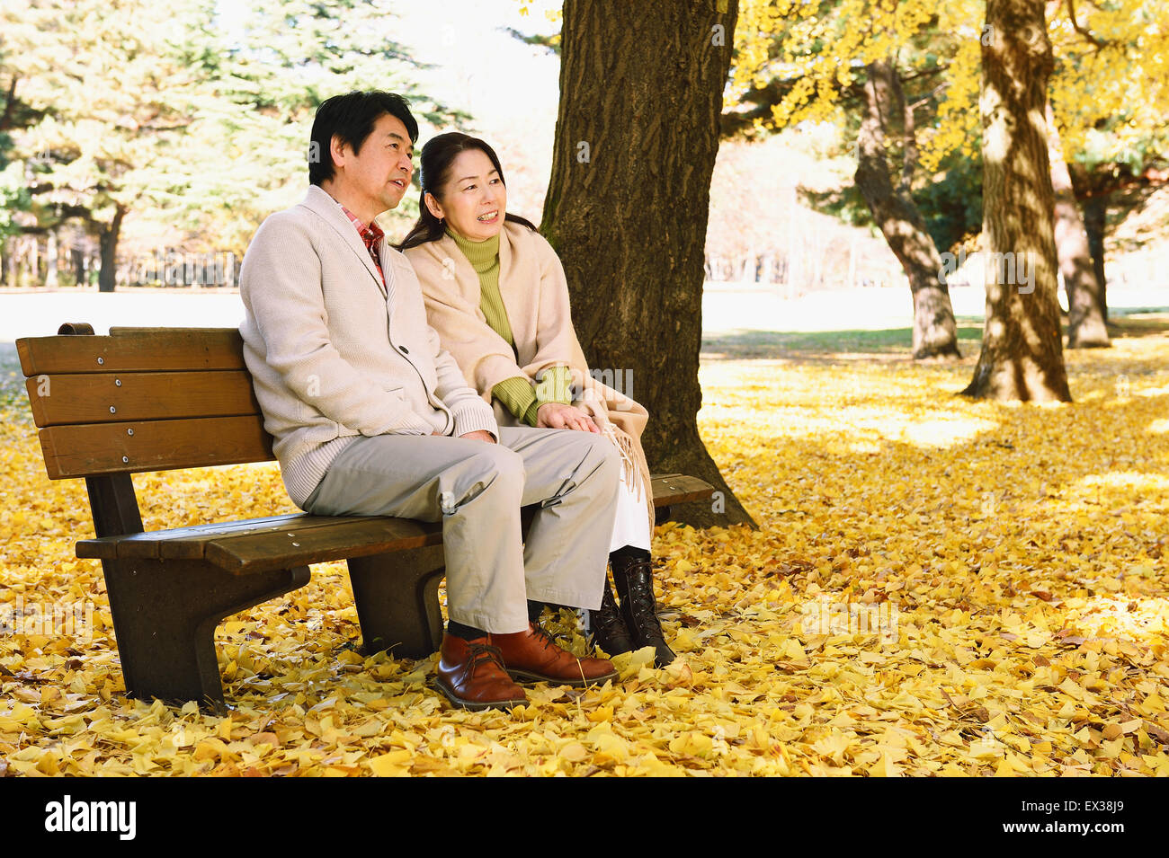 La haute couple japonais assis sur un banc dans un parc de la ville Banque D'Images