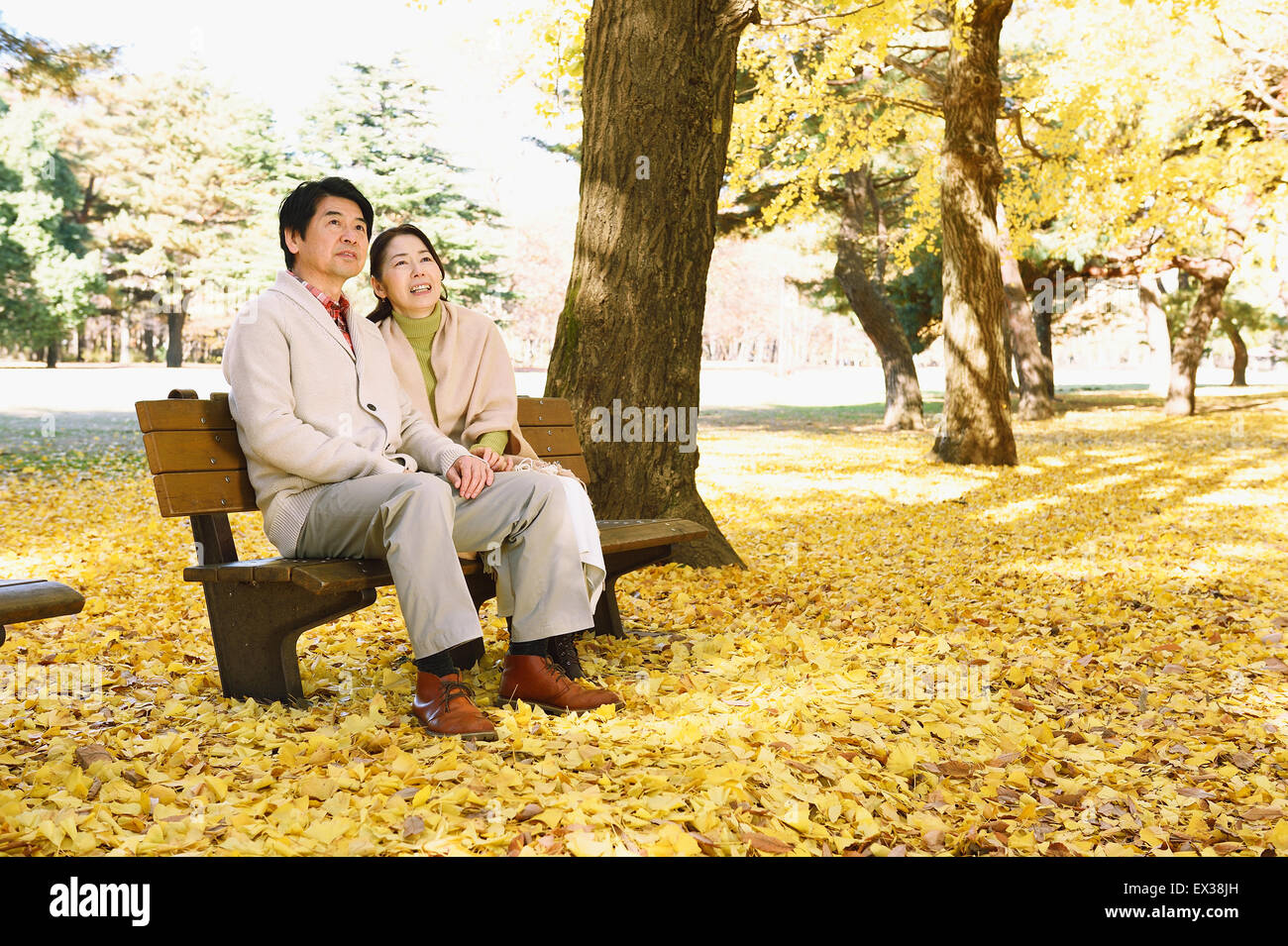 La haute couple japonais assis sur un banc dans un parc de la ville Banque D'Images